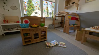 Kinderfreundlicher Spielbereich mit Holzküche, Lernmaterialien und natürlichen Spielzeugen für entwicklungsförderndes Spielen