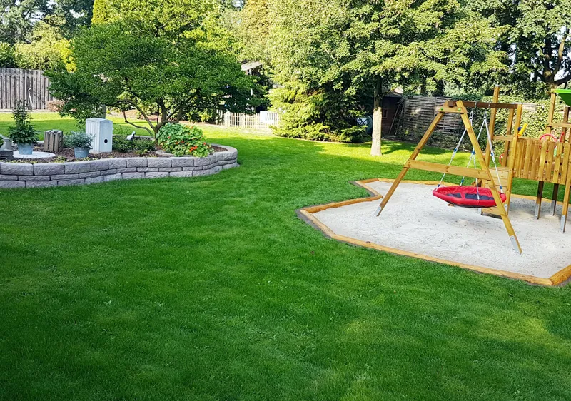 Großer Garten mit Sitzbereich, Sandkasten und natürlichen Spielmöglichkeiten für Kinder