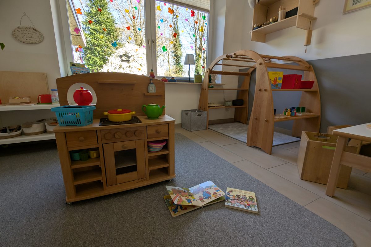 Kinderfreundlicher Spielbereich mit Holzküche, Lernmaterialien und natürlichen Spielzeugen für entwicklungsförderndes Spielen