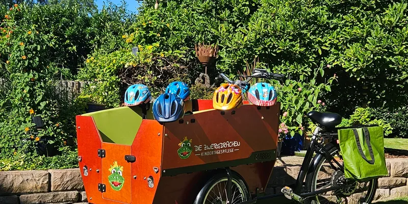 Lastenfahrrad im Garten bereit für den nächsten Ausflug – sicheres Transportfahrrad mit Helmen