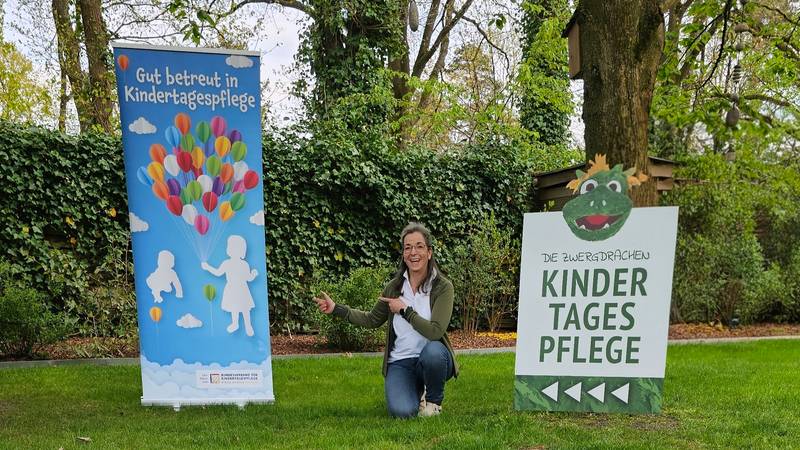 Bärbel Zisenis, qualifizierte Tagesmutter vor dem Eingang der Kindertagespflege Die Zwergdrachen in Celle mit Werbebanner und Standortschild