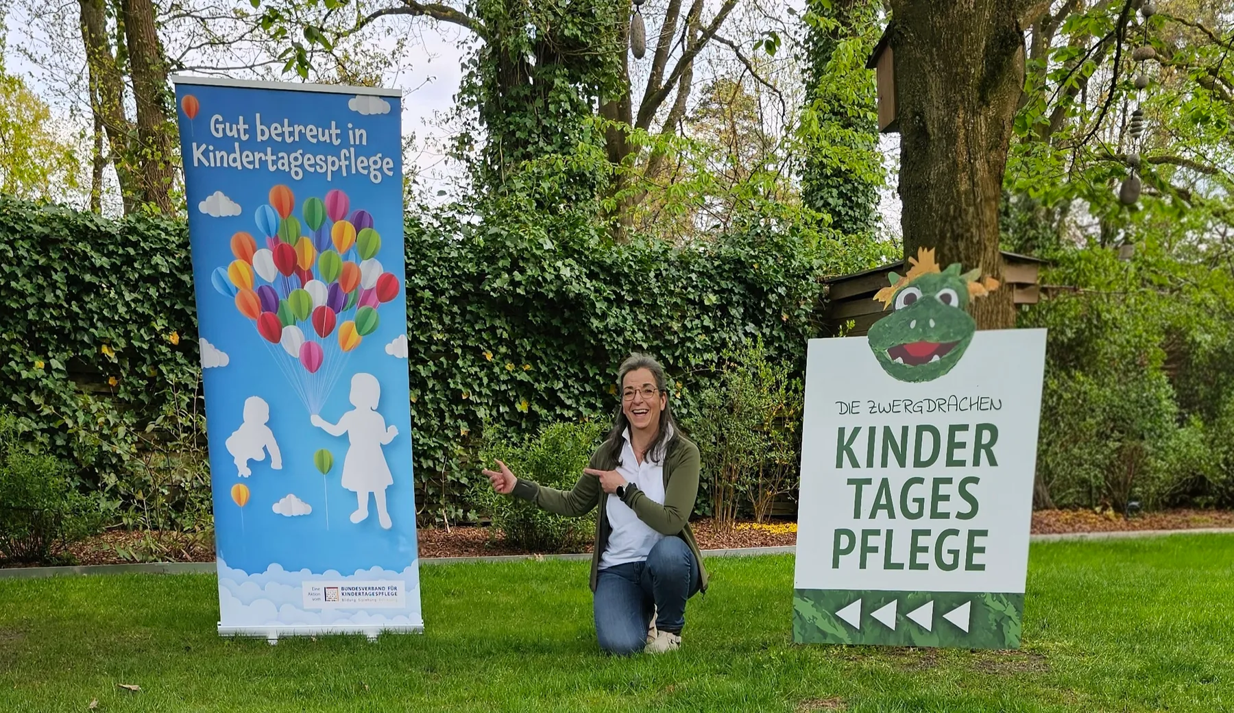 Bärbel Zisenis, qualifizierte Tagesmutter vor dem Eingang der Kindertagespflege Die Zwergdrachen in Celle mit Werbebanner und Standortschild
