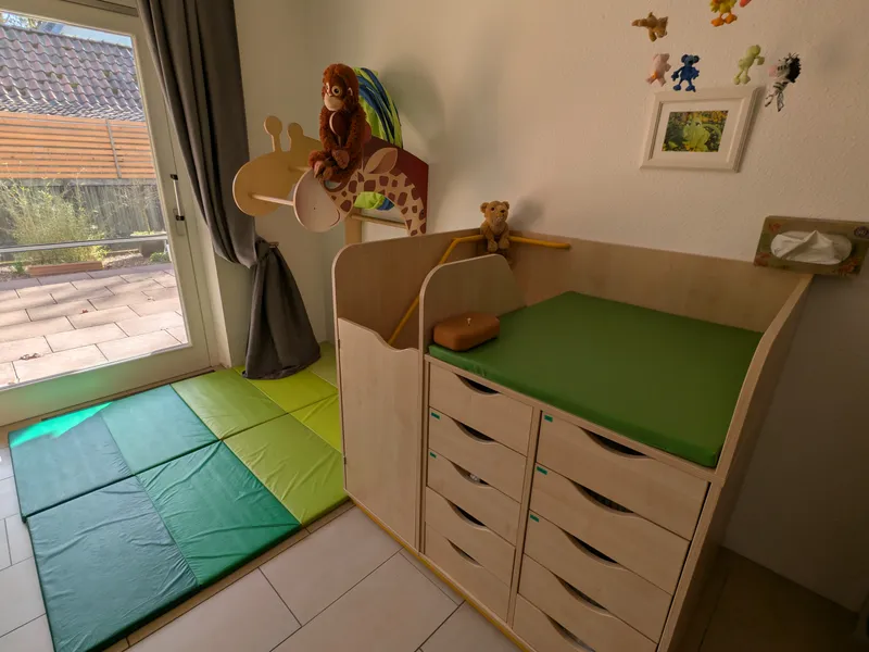 Sichere Wickelstation mit gepolsterten Matten und kindgerechten Kletterelementen für selbstständige Bewegungsentwicklung